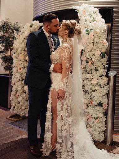 Brautpaar vor Blumenbogen